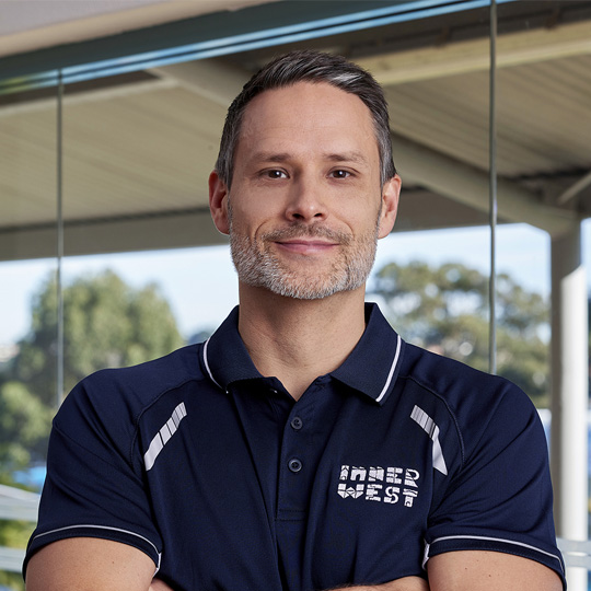 Personal trainer John smiling at the camera with arms crossed wearing a navy Inner West Council branded shirt